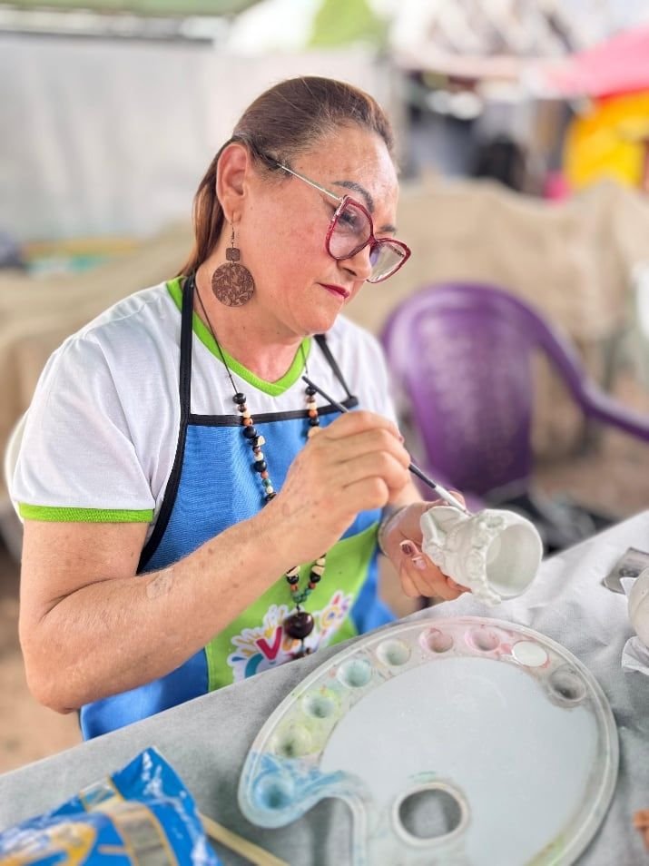 Artesã de avental pintando uma garrafa plástica reaproveitada