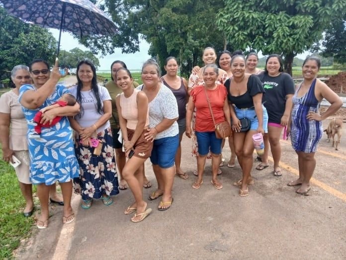 Grupo de mulheres posando juntas numa rua de terra