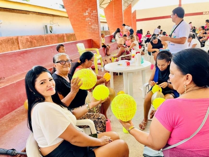 Mulheres sentadas em roda trabalhando em bolas de artesanato amarelas