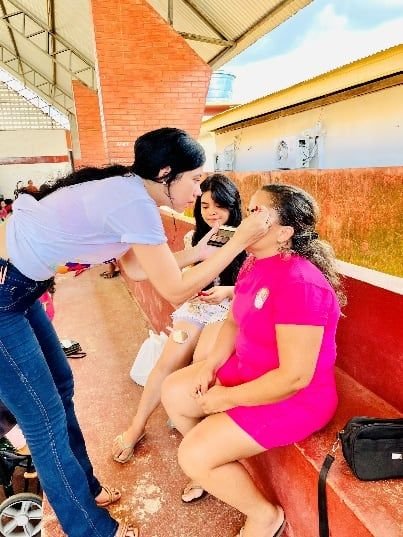 Mulher maquiando outra participante