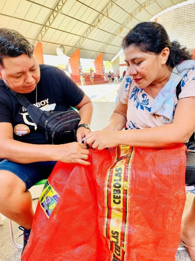 Duas pessoas segurando uma bolsa feita de saco de rede vermelha