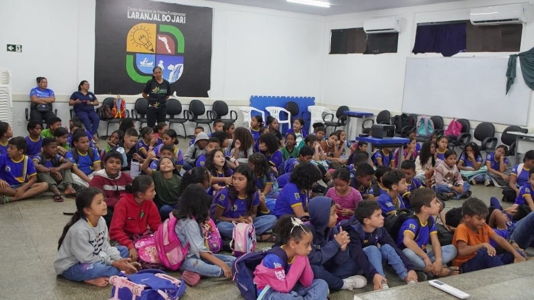 Crianças sentadas no chão de um auditório