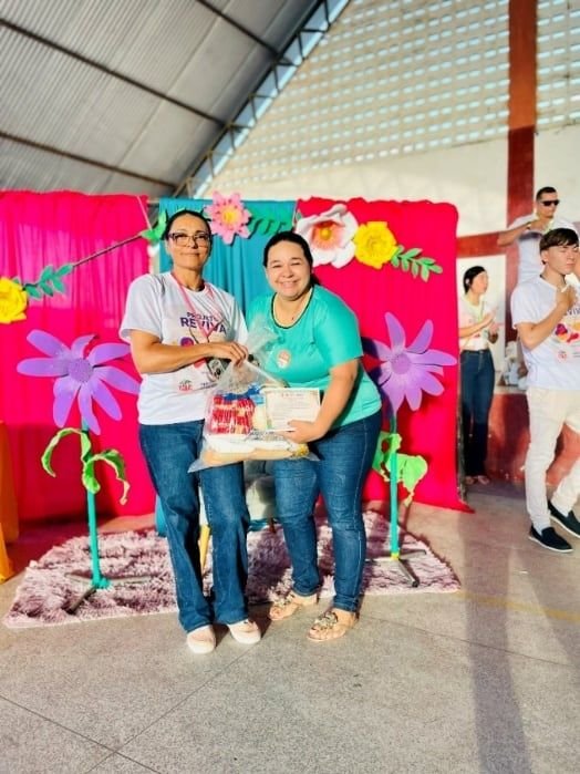 Duas mulheres segurando uma cesta diante de um painel decorado com flores