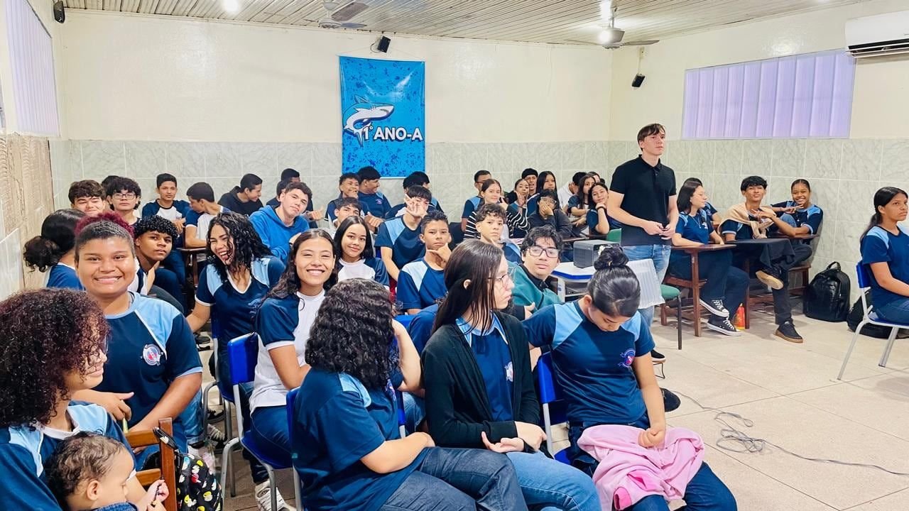 Estudantes de uniforme sentados numa sala, assistindo a uma apresentação