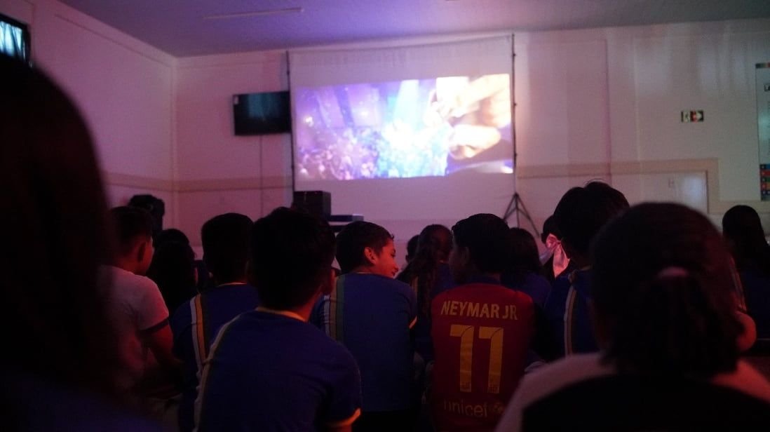 Plateia assistindo a um filme projetado numa sala escura