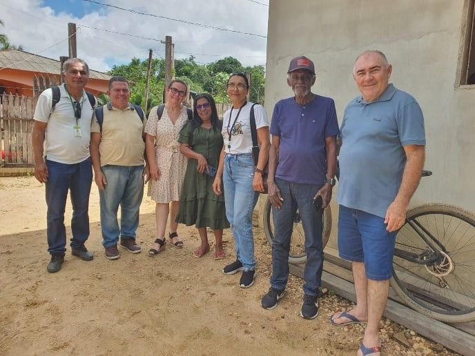 Grupo de pessoas posando juntas numa rua de terra