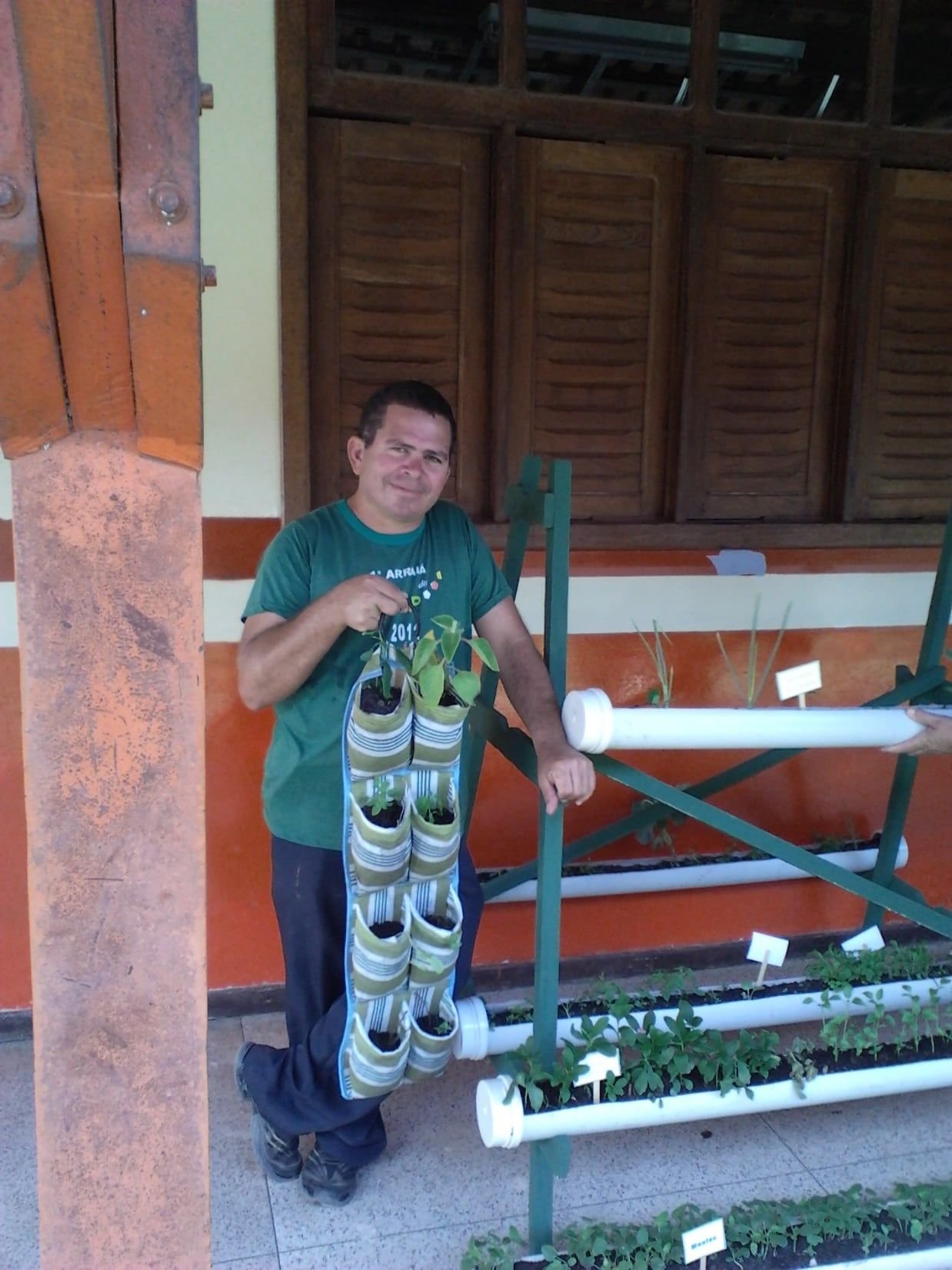 Homem ao lado de uma estrutura vertical de PVC com mudas