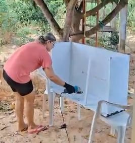 Mulher pintando uma cadeira de branco ao ar livre